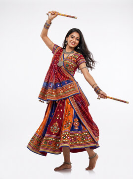 Female Indian folk dancer performing dandiya with decorated sticks and colorful embroidered attire