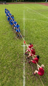 Group of athletes competing in a tug of war on a grassy field  