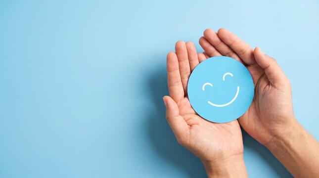 Blue smiley face held in human hands, mental health awareness and positive feedback concept, minimalist composition with copy space