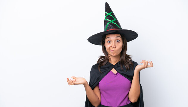 Young hispanic woman dressed as witch over isolated background having doubts while raising hands