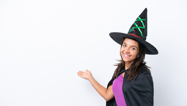 Young hispanic woman dressed as witch over isolated background extending hands to the side for inviting to come