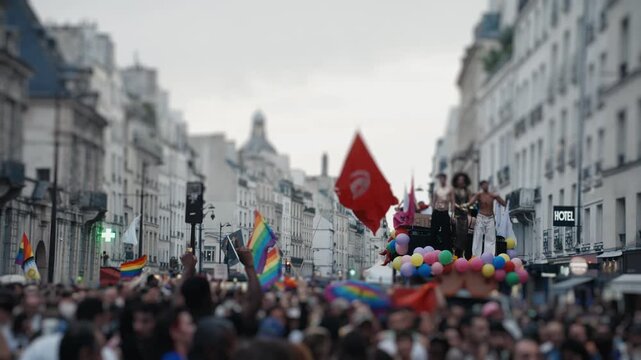 Pride parade float moving through a crowded city street