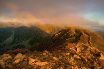 Breathtaking autumn landscape of Western Tatras mountain ridge at sunset. Golden sunlight hitting the rocky peaks of Volovec and Rohace under a cloudy sky. Perfect for travel and nature themes. © Ivan