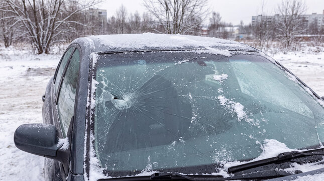 Car windshield broken by vandalism or accident in winter, showing impact damage and cracked glass