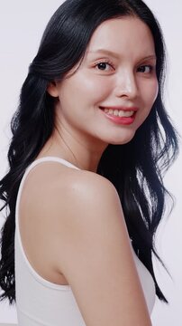 A beautiful Asian woman with clean glowing skin smiles at the camera. Perfect for skincare, beauty product, and cosmetic advertisements.