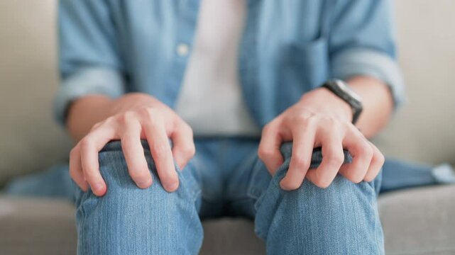 Closeup legs shaking in a guy in blue jeans. Uncontrollable leg shaking. Severe stress in a guy. A man is worried while sitting on a sofa. Health problems and sickness