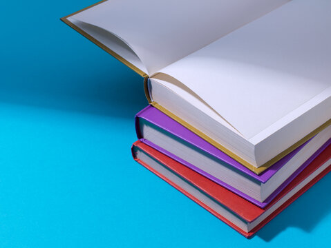Open Book on Top of Colorful Stack of Hardcovers