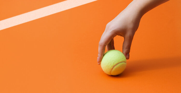 Female Tennis Player Hand Picking Up Ball on Orange Clay Court