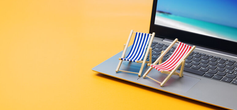 Online Vacation Booking Concept with Miniature Deck Chairs on Laptop Keyboard