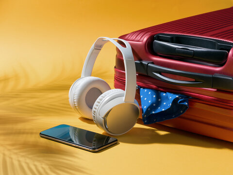 Red Suitcase and Headphones with Palm Leaf Shadows for Tropical Summer Vacation Concept