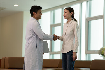 Doctor greeting female patient with handshake during medical consultation in modern clinic with male patient © Stock Media Labs