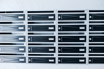 Row of metal mailboxes with name slots and locks in a residential apartment building lobby. Real estate rental concept. © EdNurg