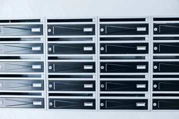 Row of metal mailboxes with name slots and locks in a residential apartment building lobby. Real estate rental concept. © EdNurg