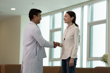 Doctor greeting woman patient with handshake during medical consultation in modern clinic in bright clinical setting © Stock Media Labs