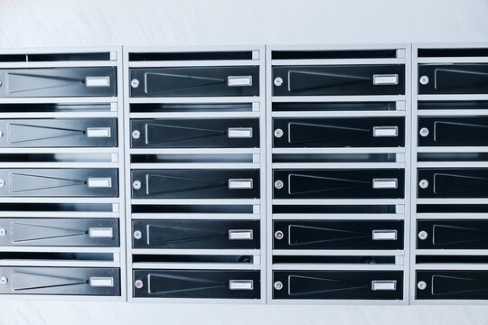 Row of metal mailboxes with name slots and locks in a residential apartment building lobby. Real estate rental concept.