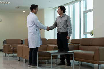 Doctor greeting patient with handshake during medical consultation in hospital waiting room near bright window near bright window © Stock Media Labs