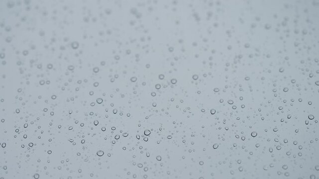Rain drop hitting window glass and sliding down