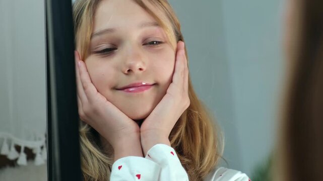 A teenage girl admires herself in the mirror close up. Concept: healthy self esteem, self love, and the mental health of adolescents and children.