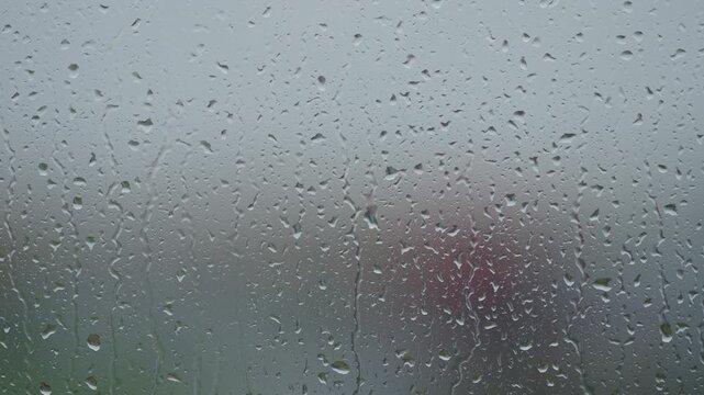 Rain drop hitting window glass and sliding down
