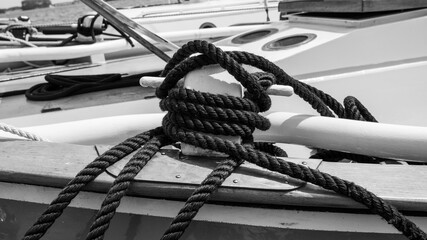 Coiled mooring rope on a wooden sailboat deck in black and white © Damien