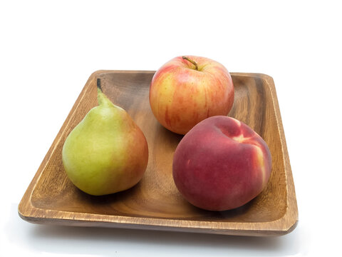 Peach, pear and apple on a wooden plate