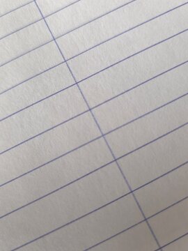 Close-up background of white lined notebook paper sheet with blue stripes at a diagonal angle.