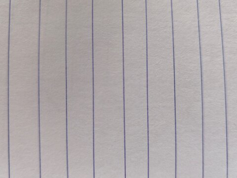 Texture background of a white lined notebook paper sheet with straight vertical blue lines.