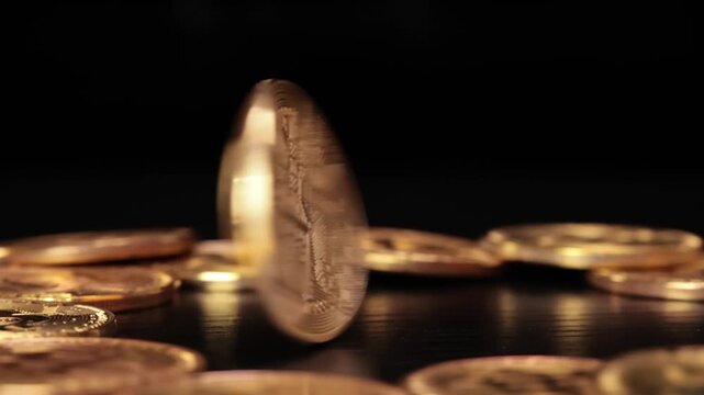 Bitcoin cryptocurrency coin spinning on a dark surface and stopping motion close up shot.