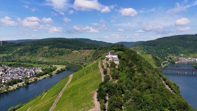 Spektakul&auml;re Drohnenaufnahme der historischen Marienburg auf dem schmalen Bergr&uuml;cken der Moselschleife bei Zell, umgeben von sonnigen Weinh&auml;ngen.