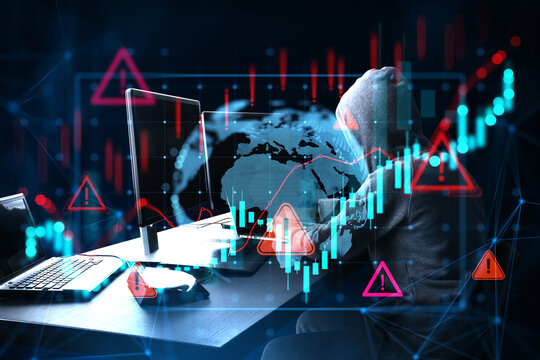 Hooded cybersecurity hacker at computer with glowing global market charts, warning symbols, and digital data network on a dark background.