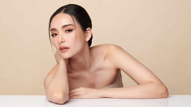 A beautiful young Asian woman with clean, fresh skin against a beige background. Skincare, facial treatment, cosmetology, beauty, and spa. An elegant portrait of an Asian woman.