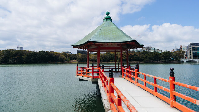 Ohori Park panorama in Fukuoka, Japan, Chuo-ku ward, Kyushu island, with pond, Ukimi-do pavilion, swan boats, bridges and city skyline near Maizuru Park, lake and promenade in a spring sunny day