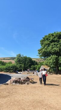 Widecombe in the Moor Devon England UK. 20.08.2026. Video,  Women take a walk across the village green during a dry summer in the west country