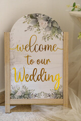 Welcome sign at a wedding event with floral decorations and a wooden frame © Dexmonk