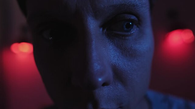 Anxious man with restless eyes looking in different directions, showing hypervigilance, fear and uncertainty while struggling with worried thoughts in a blue and red low key close up