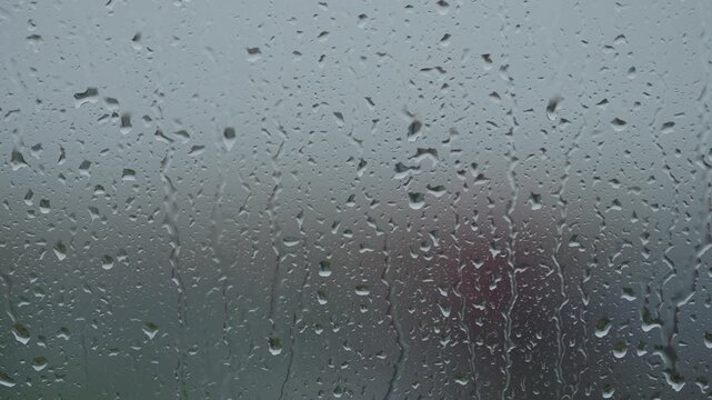 Rain drop hitting window glass and sliding down