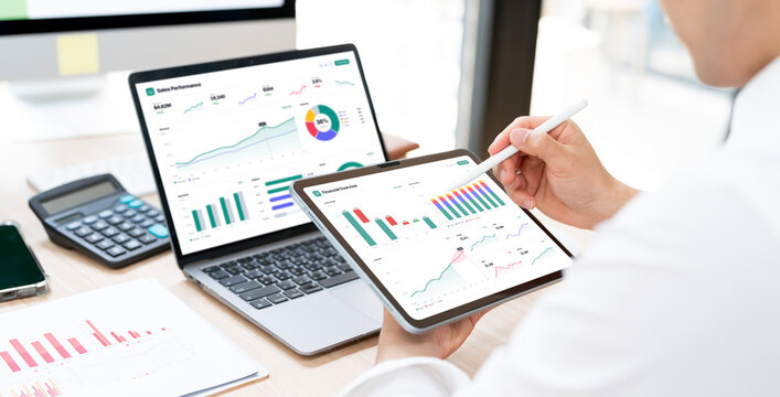 Businessman Using Stylus Pen on Digital Tablet with Financial Charts at Office Desk