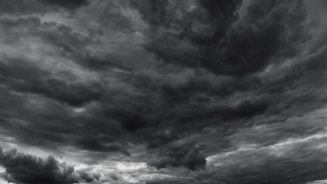 Atmospheric timelapse nature background featuring heavy dark storm clouds filling the frame with dramatic textures and intense grey tones for a moody weather concept