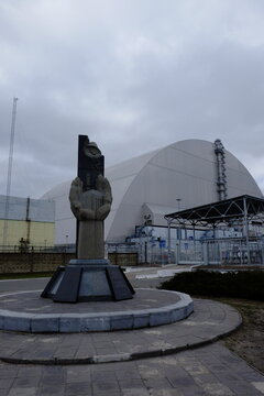 Pripyat, Ukraine, March 14, 2020. Monument to the liquidators of the accident at the Chernobyl nuclear power plant against the background of a protective sarcophagus.