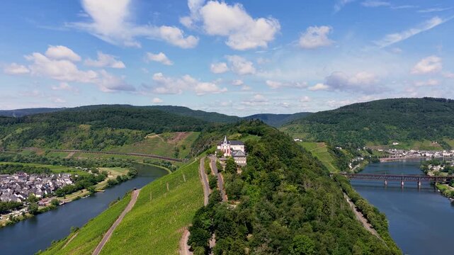 Spektakul&auml;re Drohnenaufnahme der historischen Marienburg auf dem schmalen Bergr&uuml;cken der Moselschleife bei Zell, umgeben von sonnigen Weinh&auml;ngen.