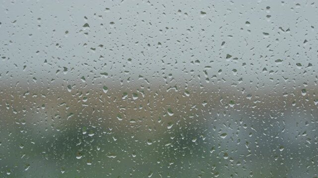 Rain drop hitting window glass and sliding down