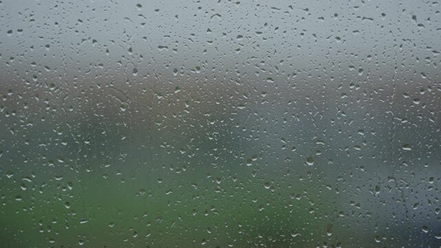Rain drop hitting window glass and sliding down