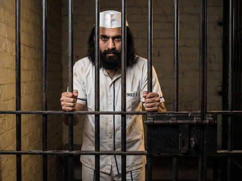Indian Prisoner Standing Behind Jail Bars in Prison Cell