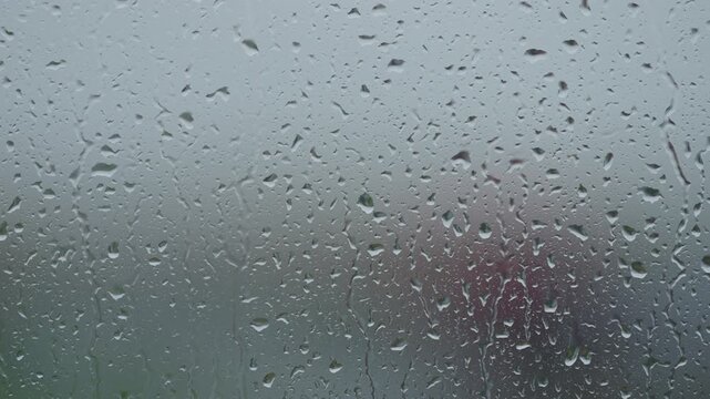 Rain drop hitting window glass and sliding down