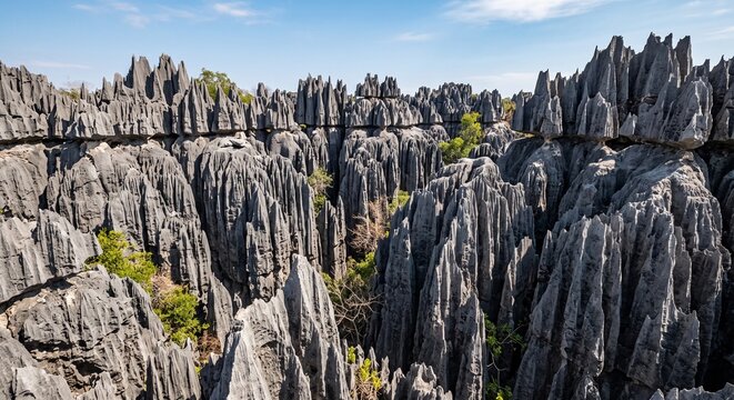 Sharp jagged rock formations and green vegetation in a rugged wilderness under a clear blue sky