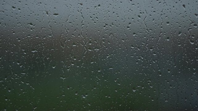 Rain drop hitting window glass and sliding down