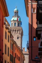 Bologna, Italy, August 7, 2026. A vertical low angle shot of the historic Accursi clock tower rising above a narrow alleyway in Bologna Italy. © JeanMarc