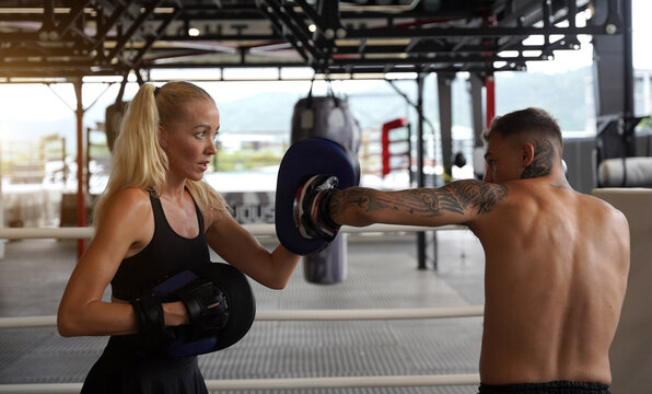 A professional fighter and coach is training in Thai boxing in the gym