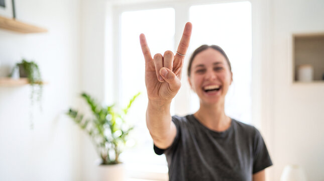 Laughing woman makes a rock horns gesture indoors