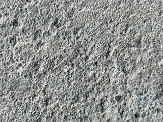 Close up macro shot of a rough grey concrete surface texture forming a solid industrial background. © Dimas Andi Juliawan